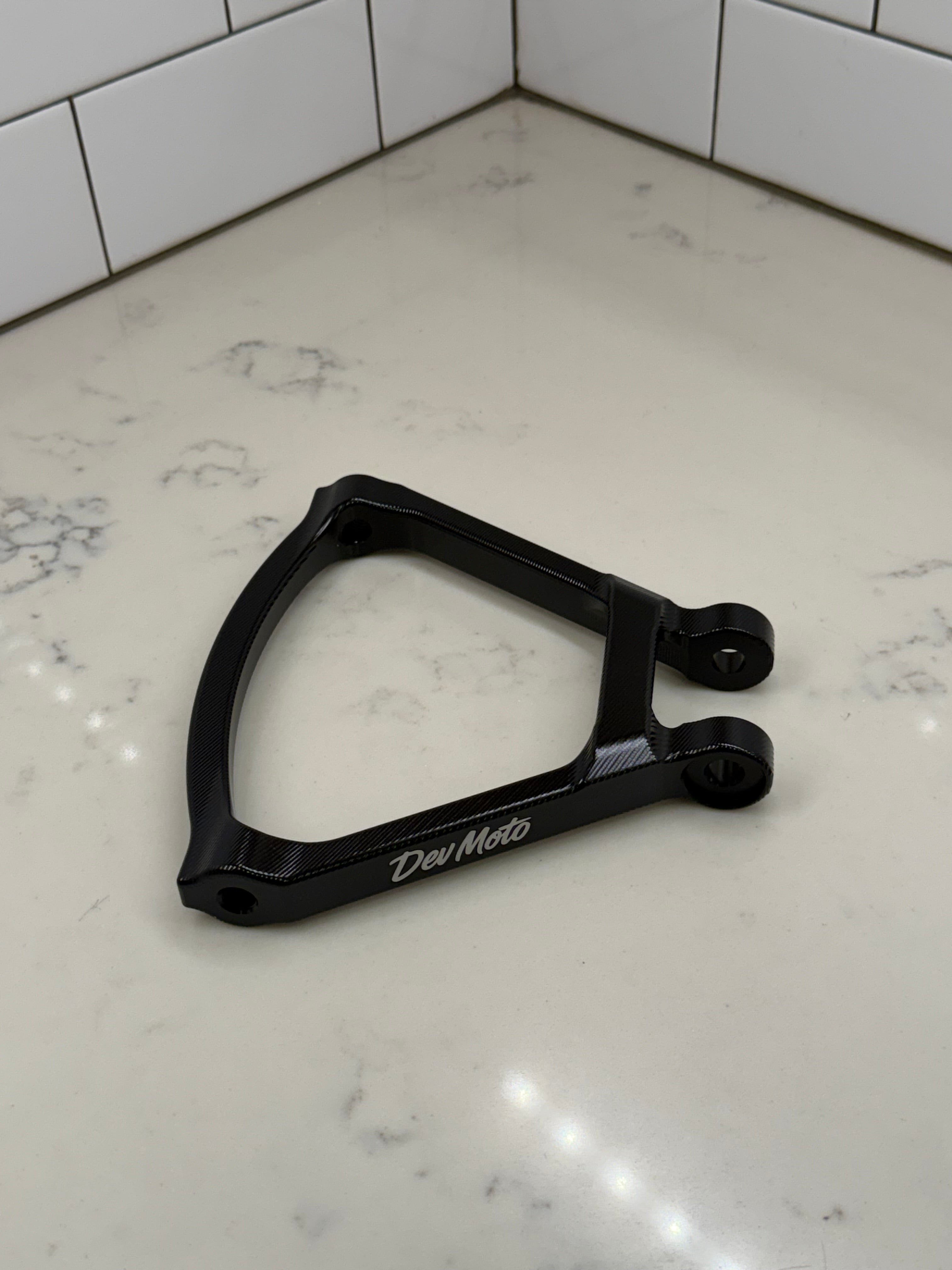 DevMoto E-Moto suspension triangle component for electric motorcycles, showcasing the durable metal part with mounting points.
