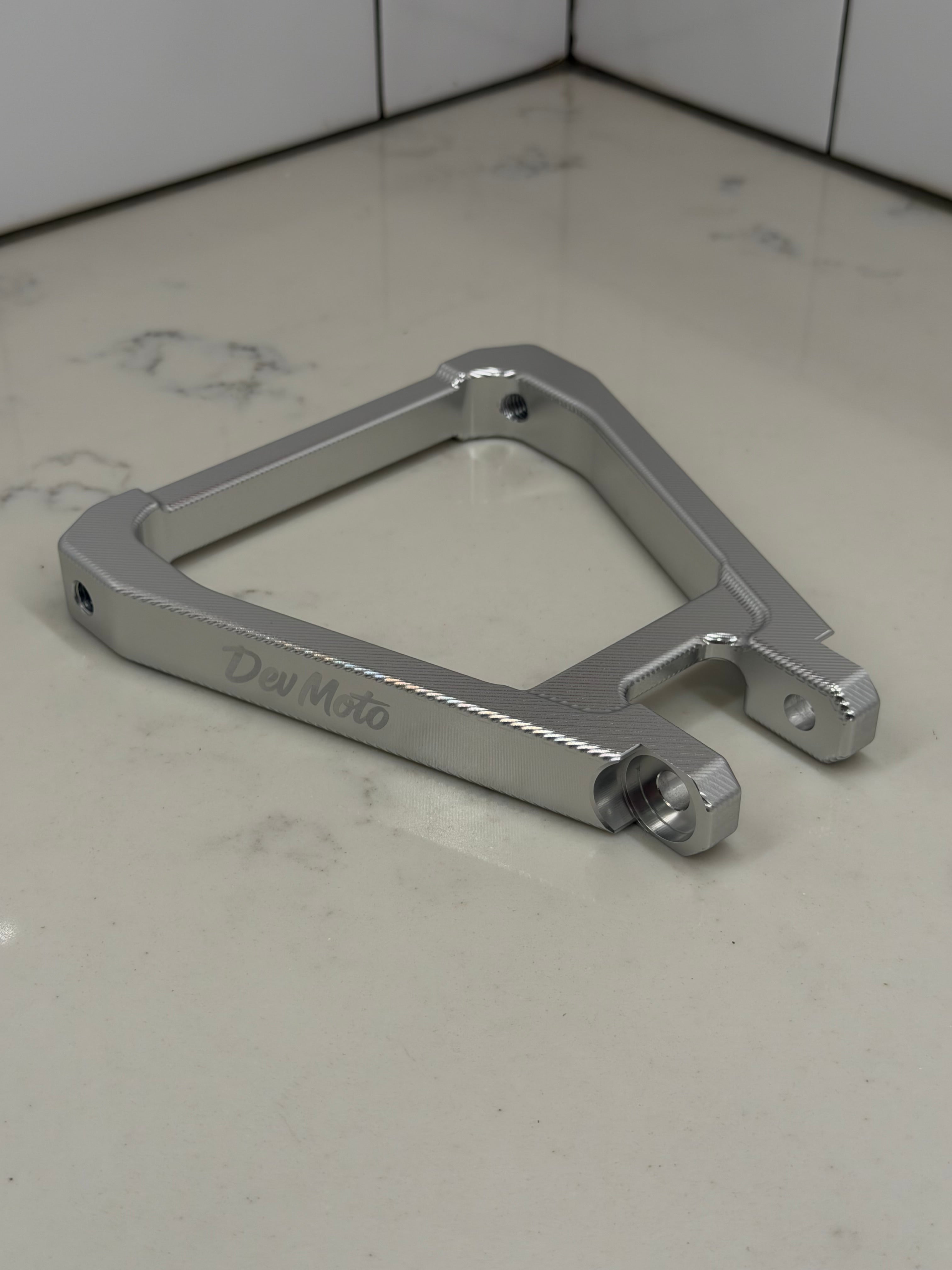 DevMoto E-Moto suspension triangle for electric motorcycle, showing metal frame component with mounting points and structural details.