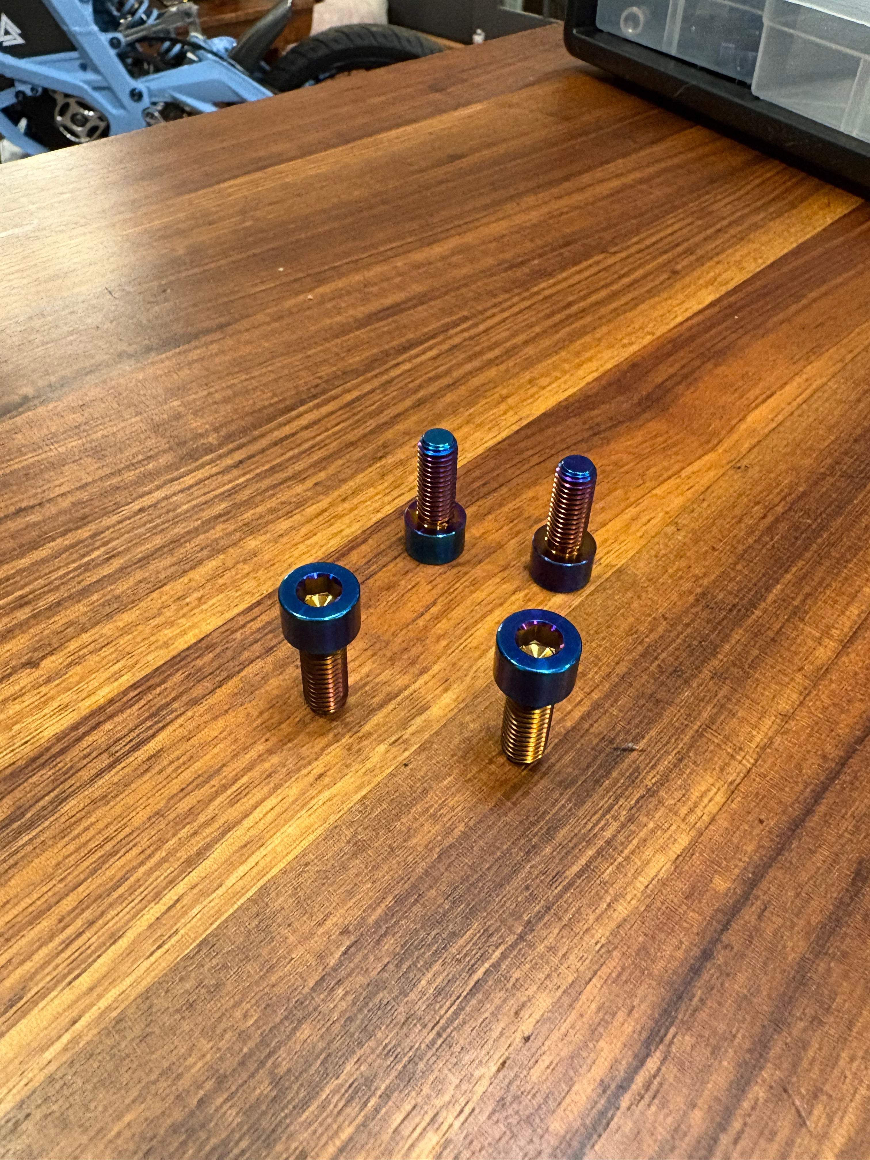 Set of four DevMoto Talaria XXX lower frame bolts for motorcycle frame assembly, shown in a close-up image.