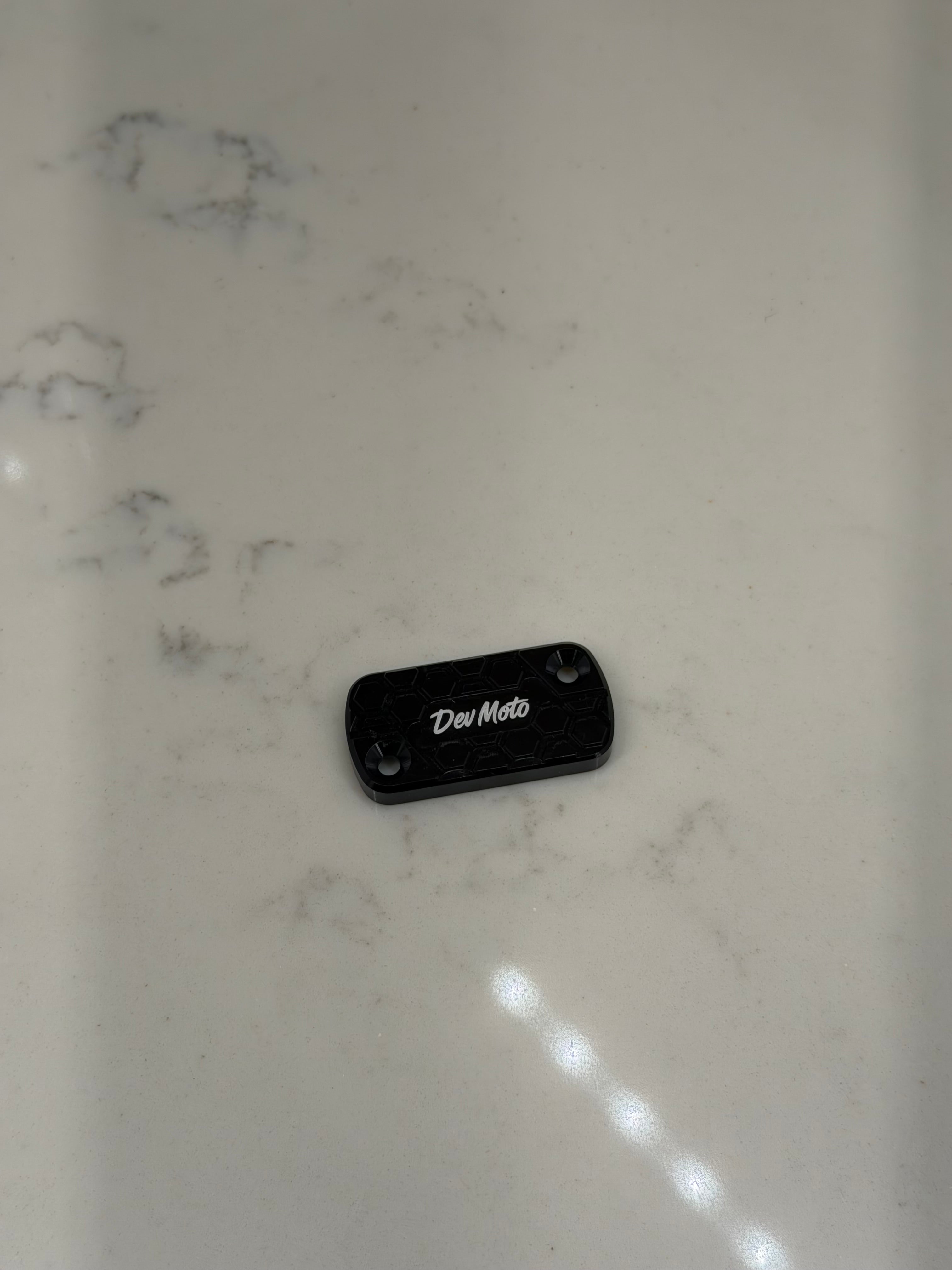 DevMoto Ultra Bee brake reservoir cap with detailed design, made of durable metal for motorcycle brake fluid reservoir.