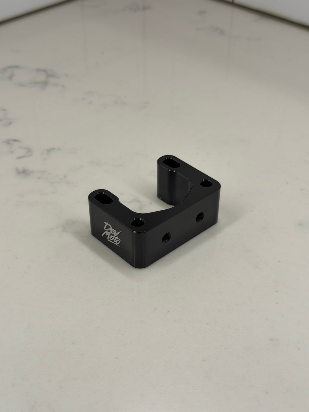 DevMoto Direct Mount Riser showing a sturdy black riser with mounting holes for motorcycle handlebars.