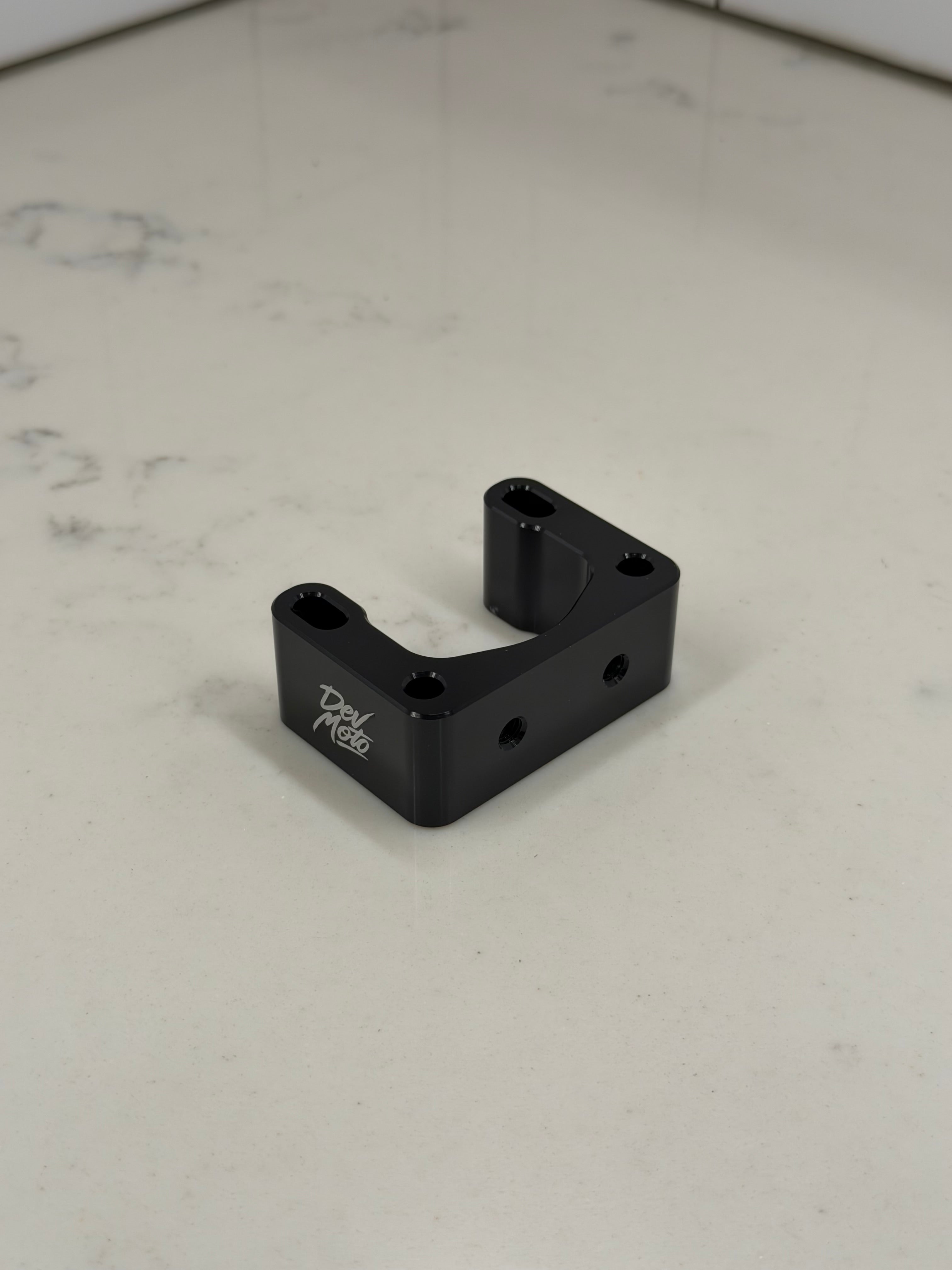 DevMoto Direct Mount Riser showing a sturdy black riser with mounting holes for motorcycle handlebars.