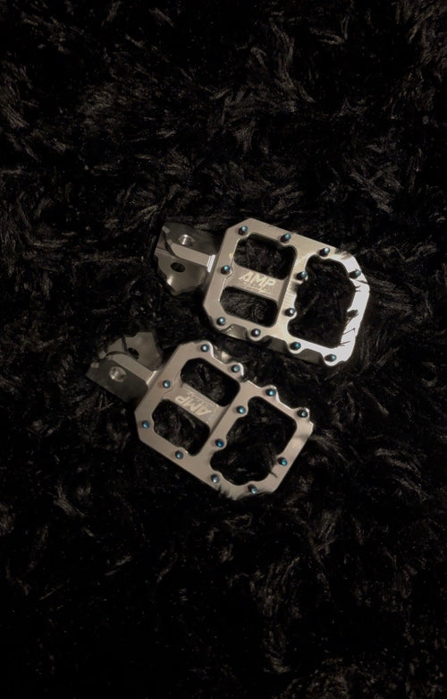 Aluminum pegs from Amp Motion, featuring sleek metal construction and a durable design for bike or skateboard use.