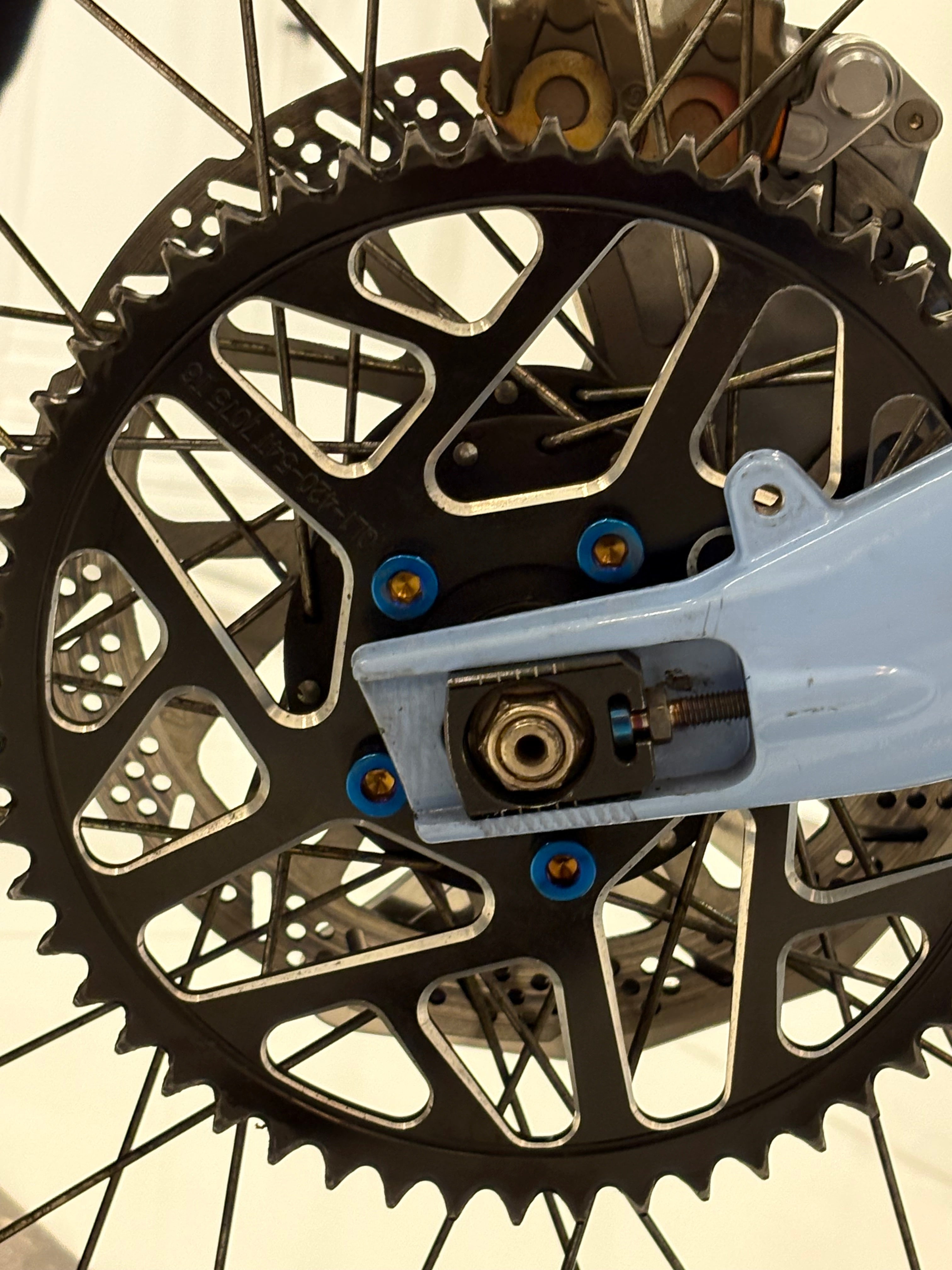 DevMoto All Emoto Sprocket Titanium Bolts installed on a motorcycle sprocket, showcasing lightweight and durable titanium construction.