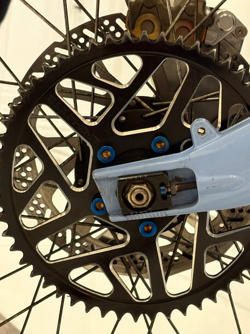 DevMoto All Emoto Sprocket Titanium Bolts installed on a motorcycle sprocket, showcasing lightweight and durable titanium construction.