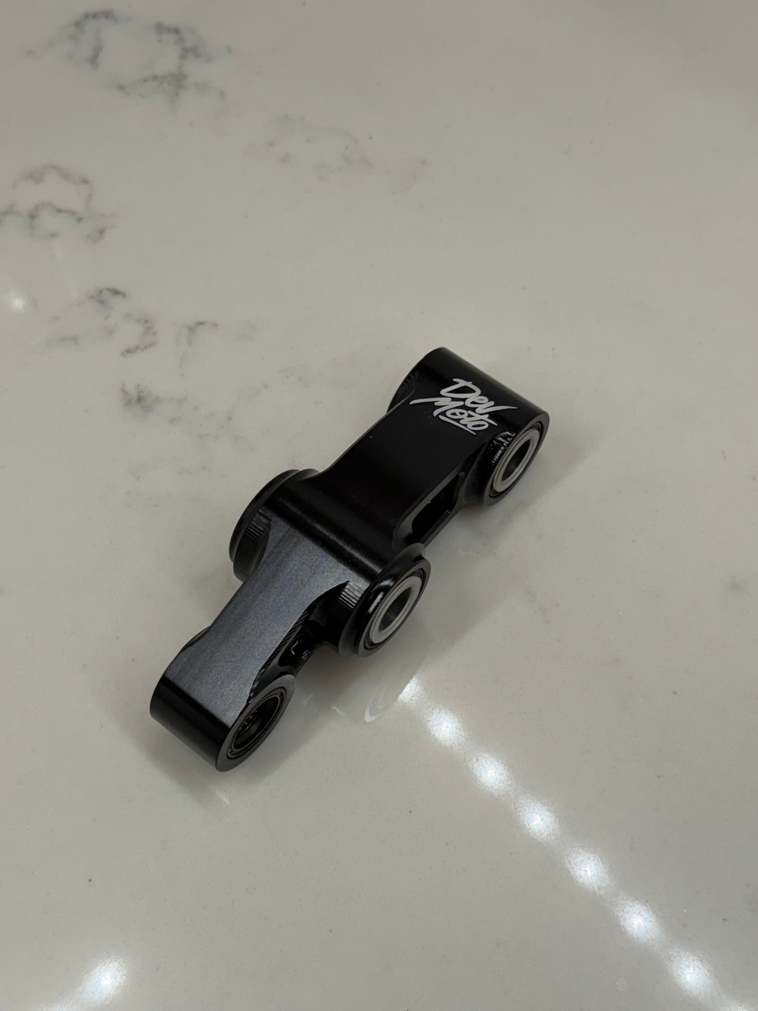 DevMoto E-Moto suspension linkage with metal components and bolts, designed for electric motorcycle suspension system.