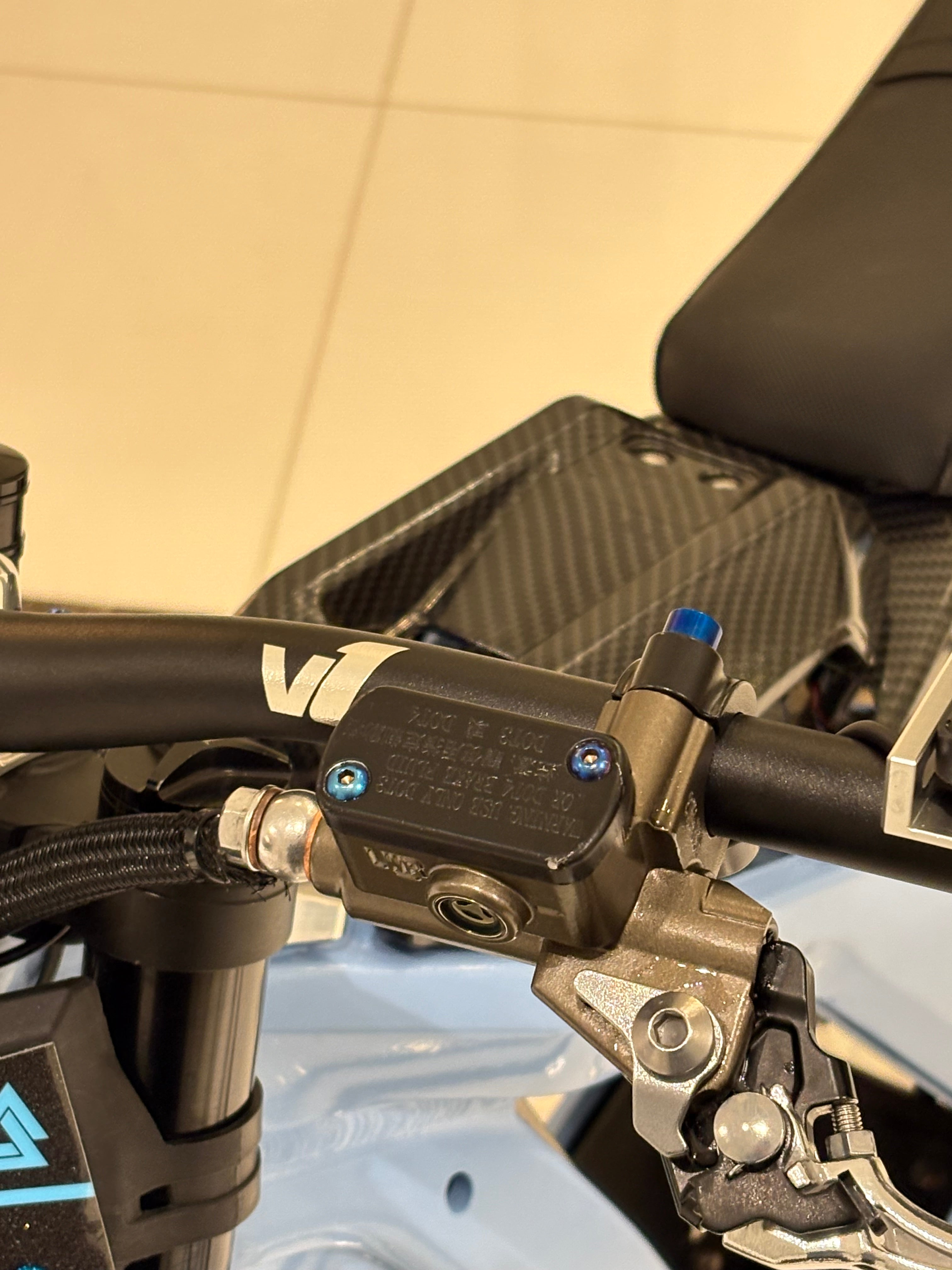 DevMoto Ultra Bee brake reservoir titanium bolts shown on a motorcycle component, highlighting lightweight and durable titanium construction.