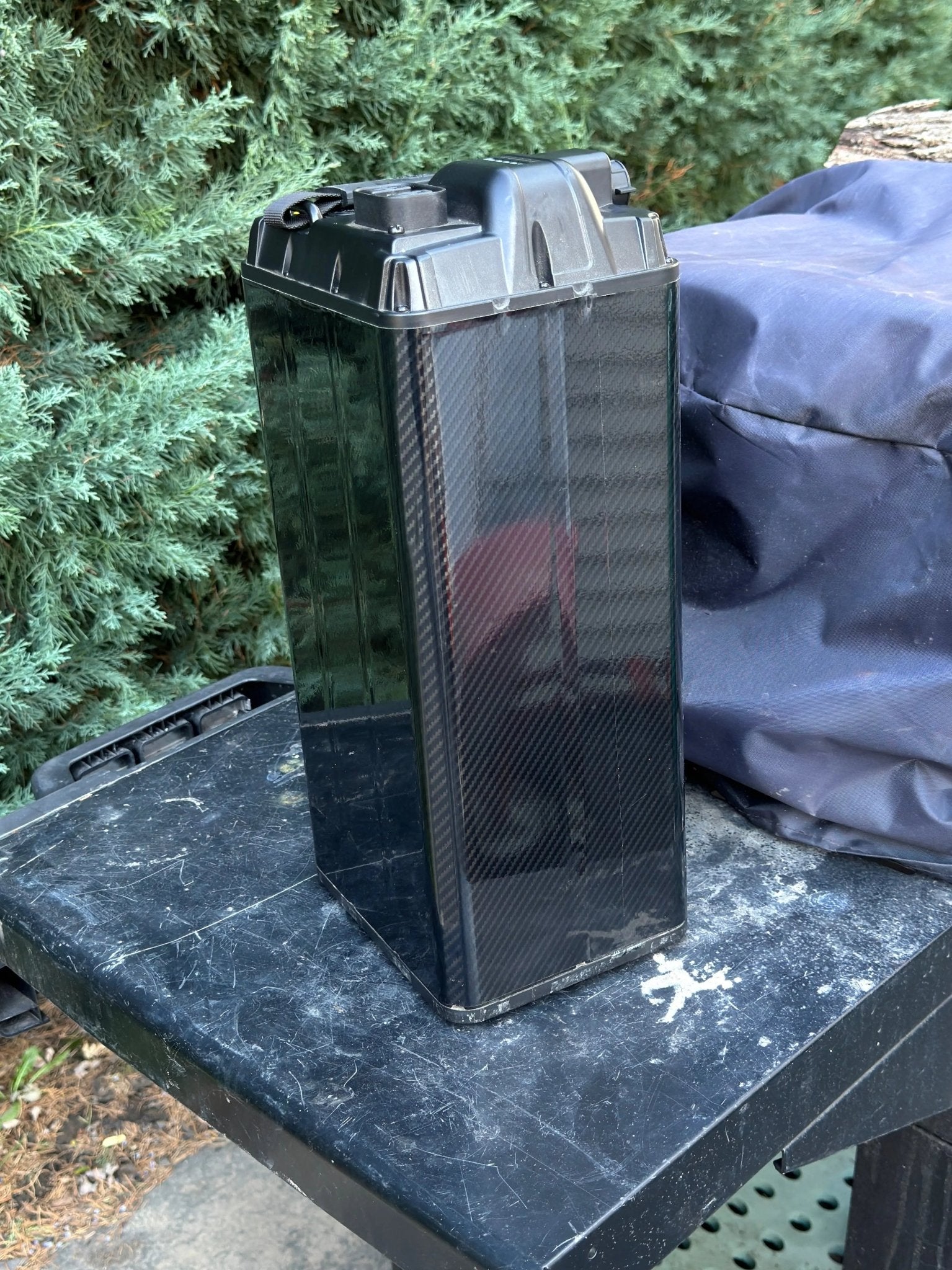 Close-up of MXwraps carbon fiber e-bike battery vinyl wrap on the corner, showcasing textured black carbon fiber finish.