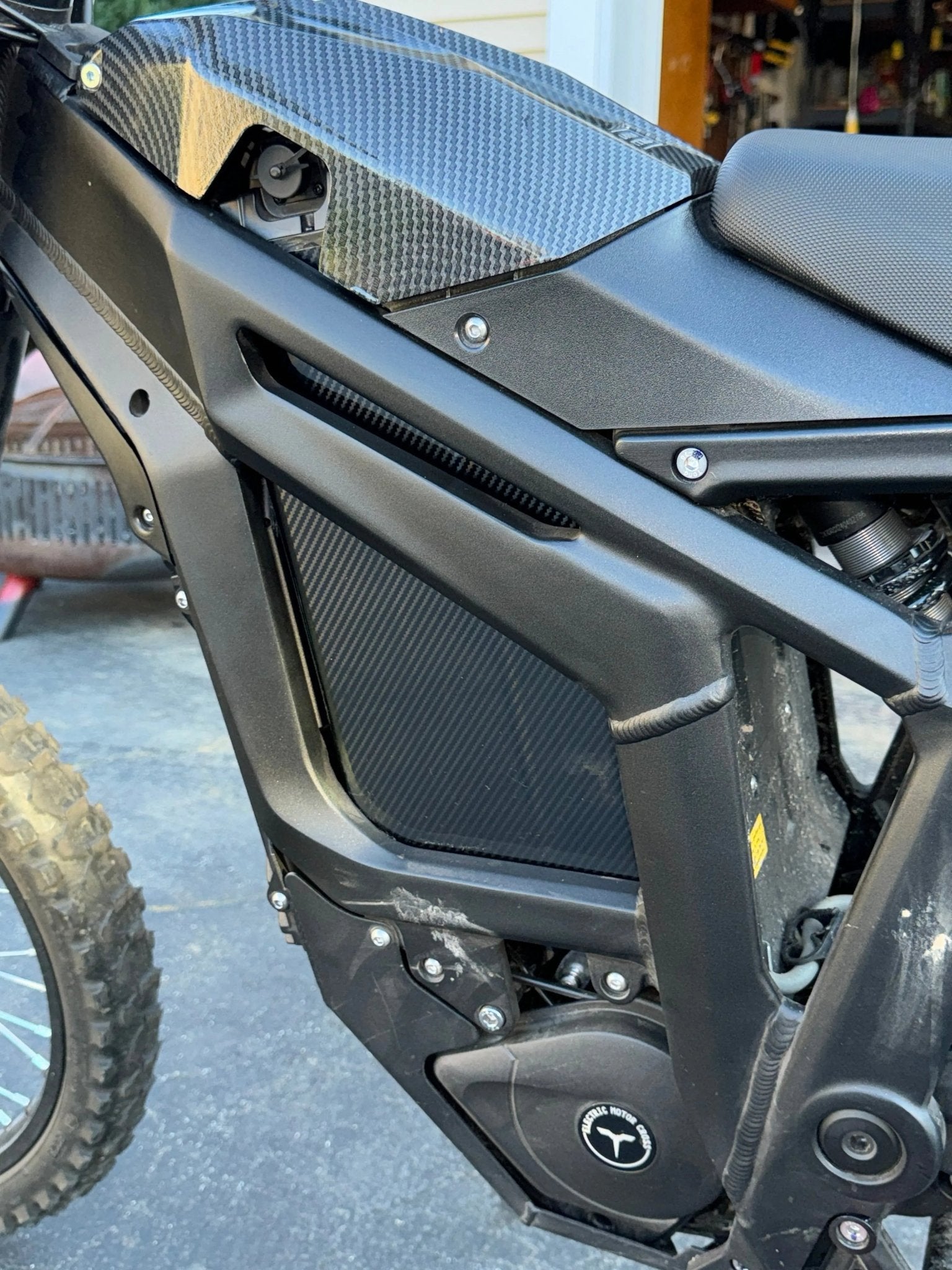 MXwraps carbon fiber battery wrap on an e-bike battery, showcasing sleek black vinyl with a textured carbon fiber pattern in sunlight.