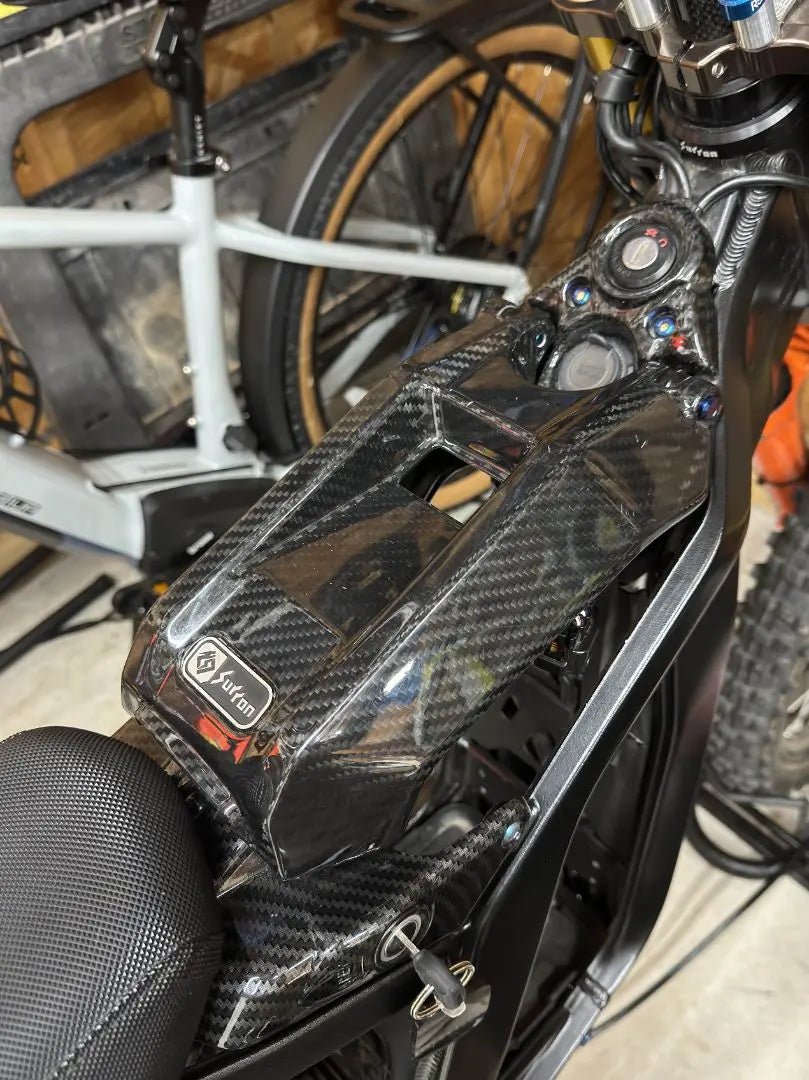 Close-up of Surron LBX electric bike battery lid with MXwraps carbon fiber vinyl wrap for a sleek, textured finish.
