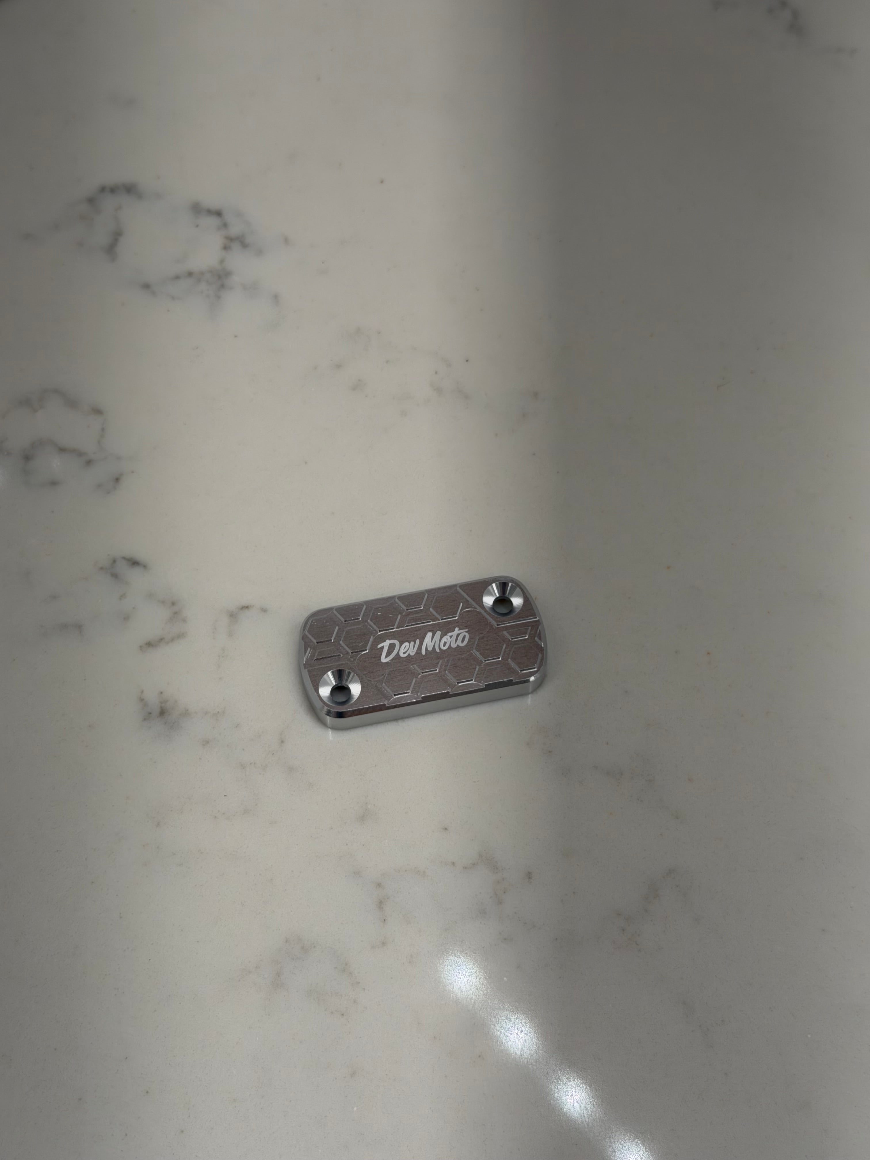 DevMoto Ultra Bee brake reservoir cap shown in close-up, featuring a durable design and precise fit for motorcycle brake systems.