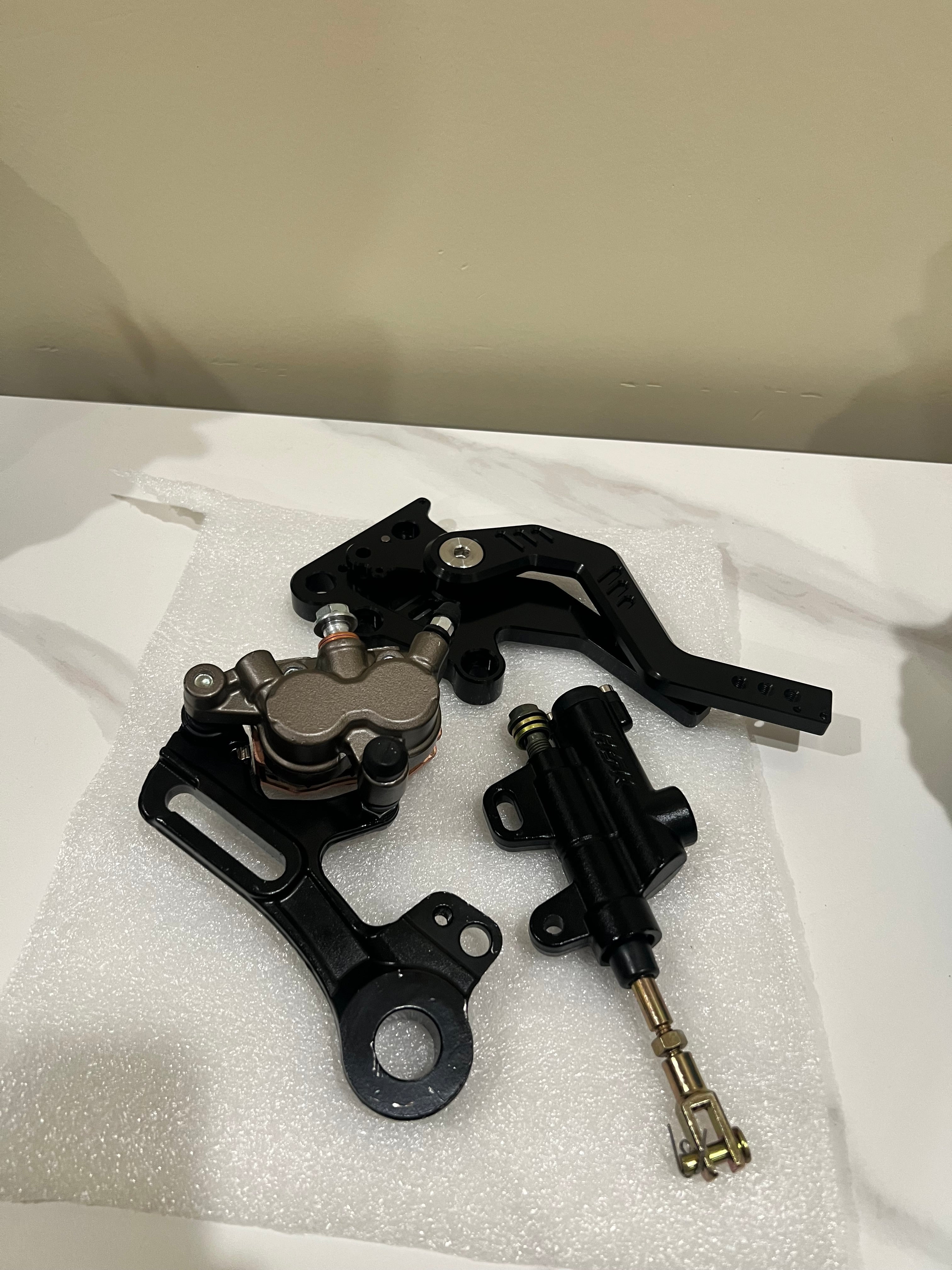 Emoto Flux Surron Light Bee/Eride Pro Moto Foot Brake Kit showing brake lever and mounting hardware on a motorcycle.