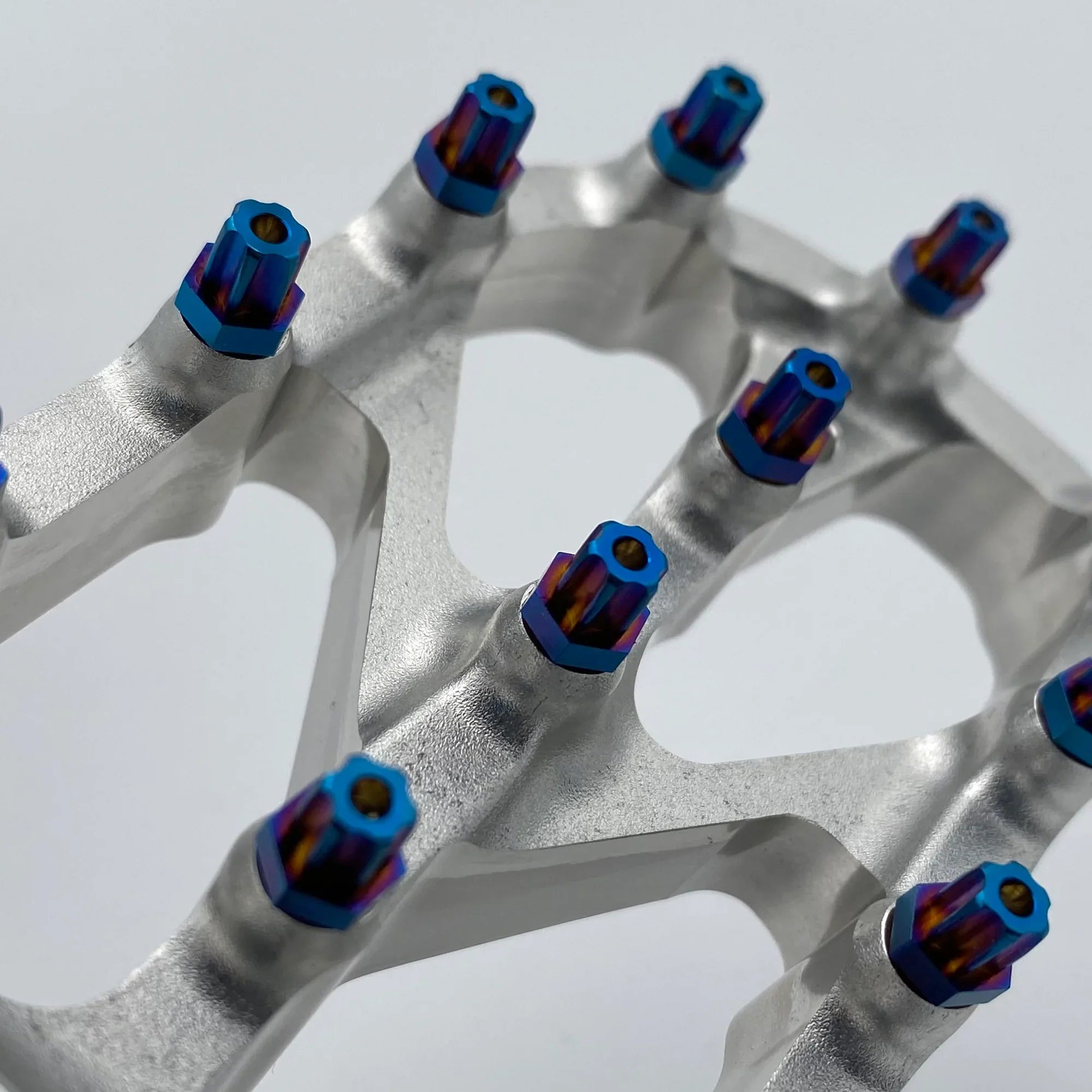 Close-up of Warp 9 Titanium Elite foot peg screws, titanium bolts from Modded Moto Co, showing the detailed torx head and sleek finish.