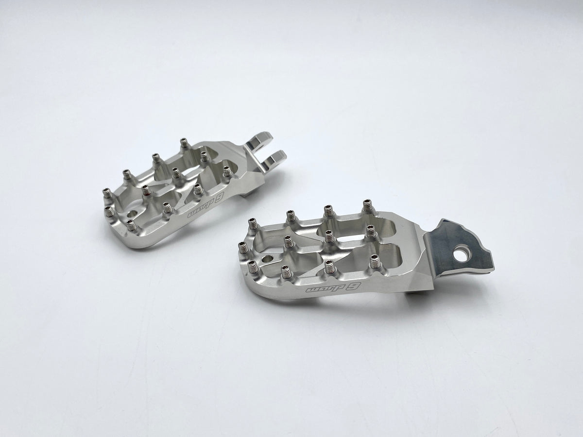 Modded Moto Co Warp 9 Talaria and Sigma Elite motorcycle foot pegs installed on a bike, showing their durable metal construction and design.