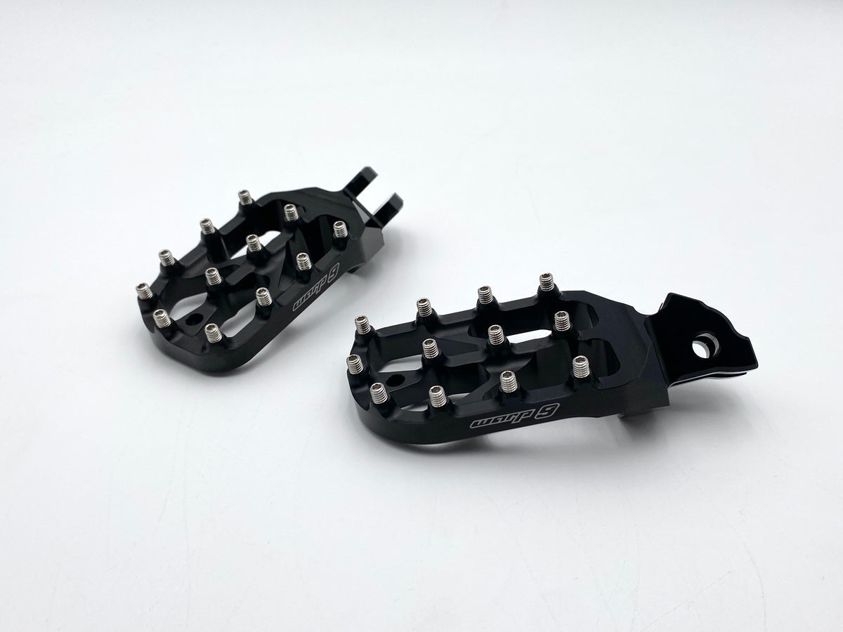 Modded Moto Co Warp 9 Talaria and Sigma Elite motorcycle foot pegs mounted on bike with detailed metal finish and mounting hardware visible