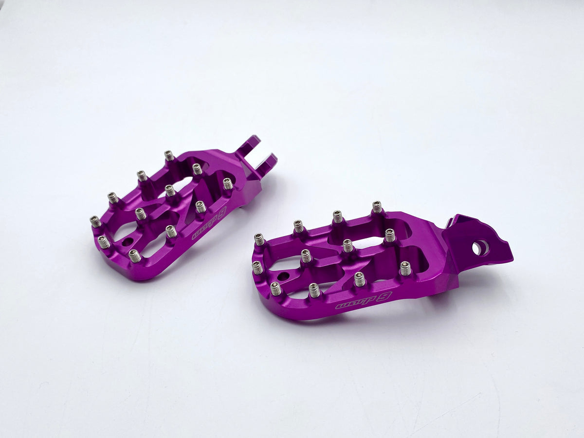 Modded Moto Co Warp 9 Talaria and Sigma Elite motorcycle foot pegs mounted on a bike, featuring durable metal construction and textured surfaces.