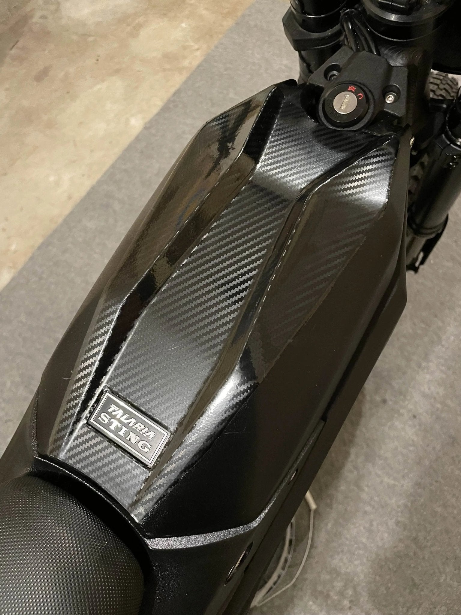 MXwraps Talaria Mx3/Mx4 carbon fiber vinyl wrap kit applied to a vehicle, showcasing the textured black carbon fiber finish.