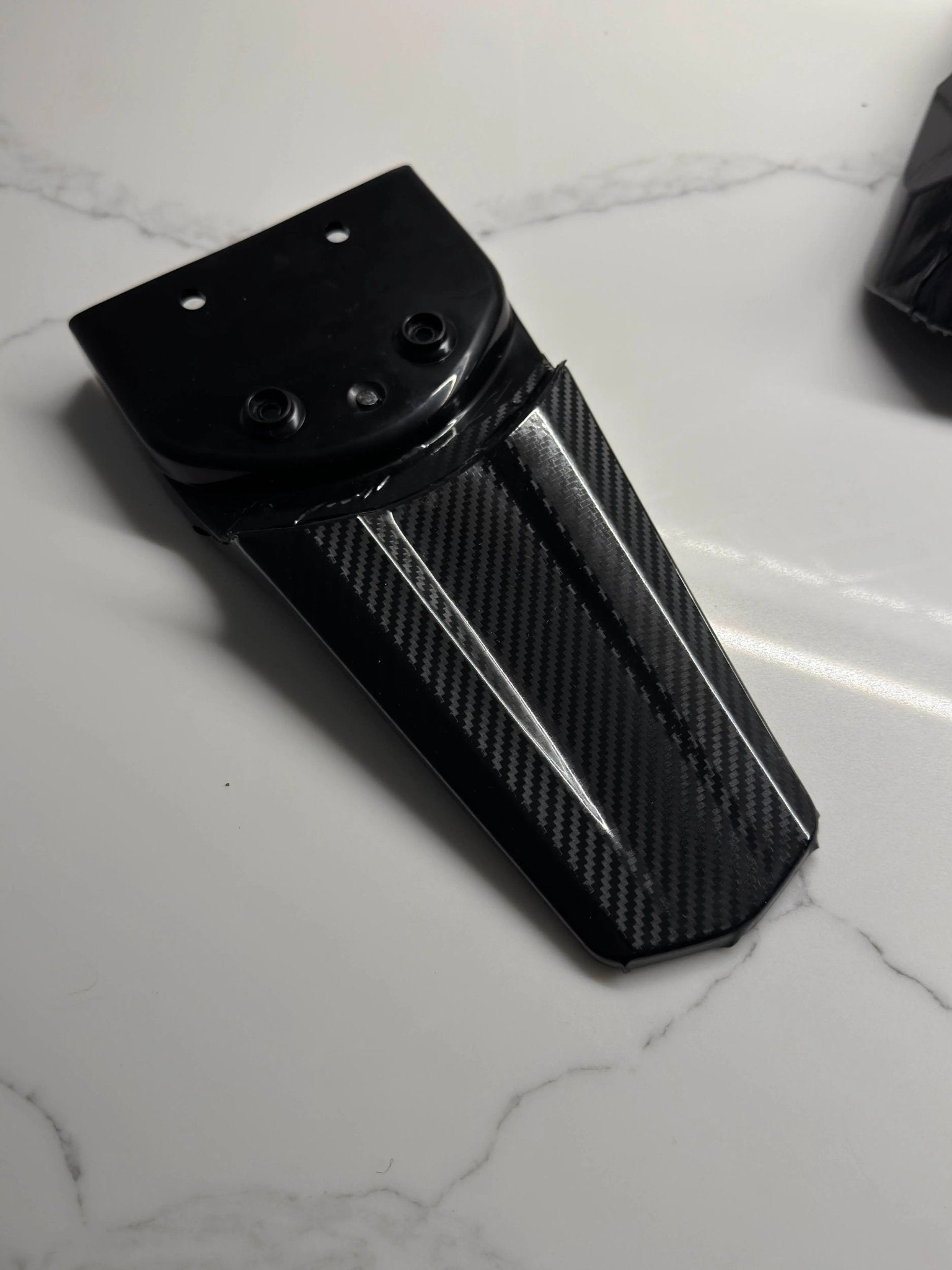 MXwraps E Ride Pro carbon fiber vinyl wrap kit applied to a vehicle, showcasing sleek black textured finish on the car's surface.