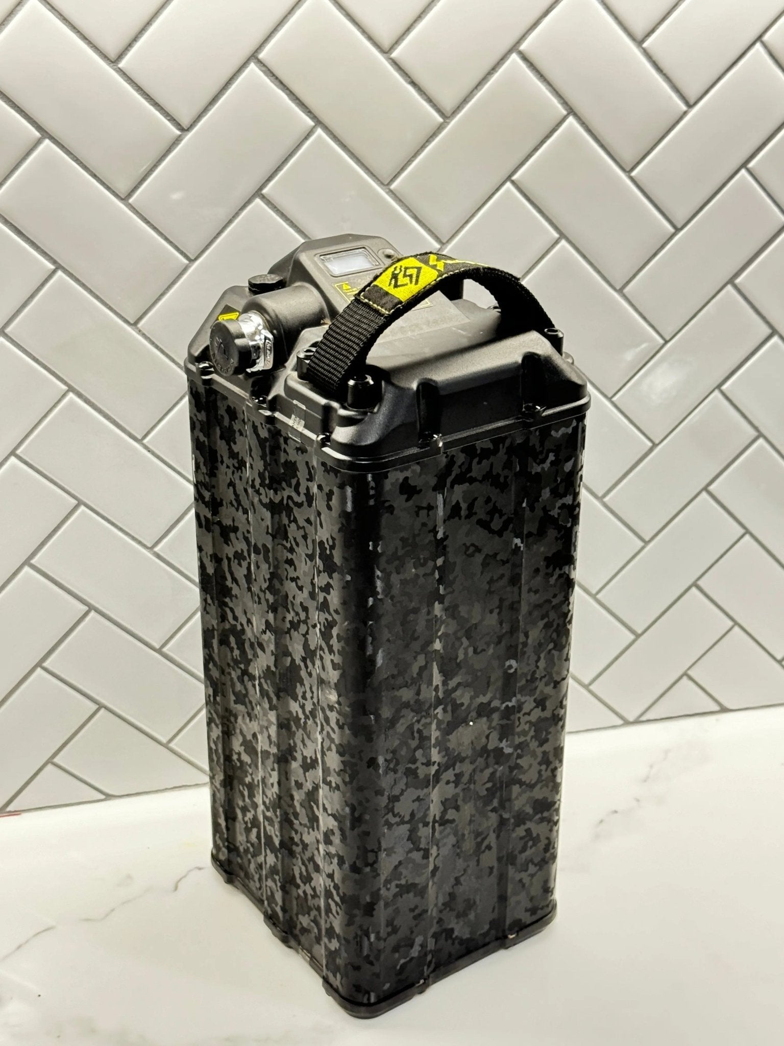 Front corner view of MXwraps ShadowSlate black camouflage vinyl wrap on e-bike battery, showcasing sleek camouflage design.