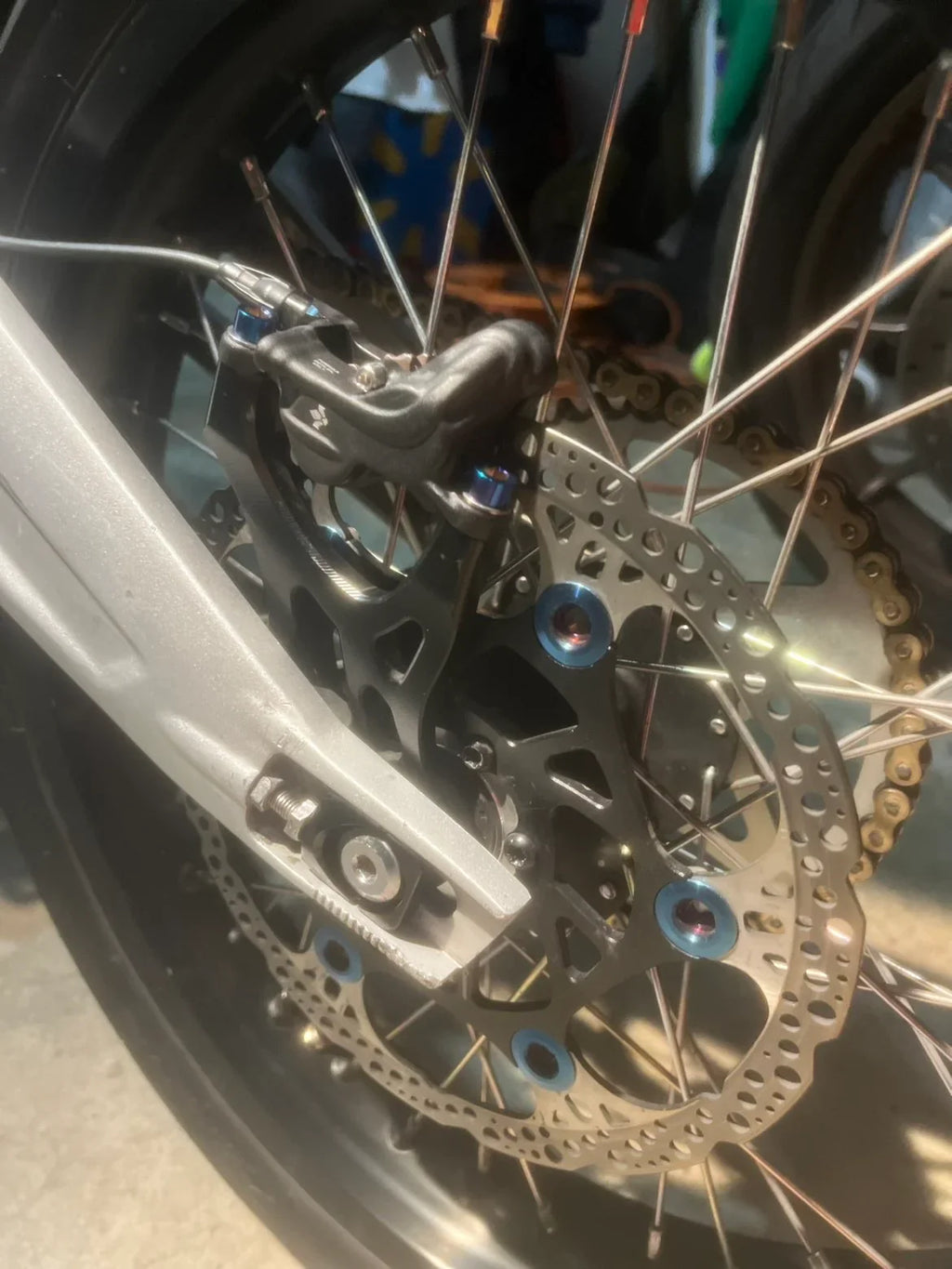 Titanium caliper bolts from DevMoto mounted on a motorcycle caliper for secure brake assembly.