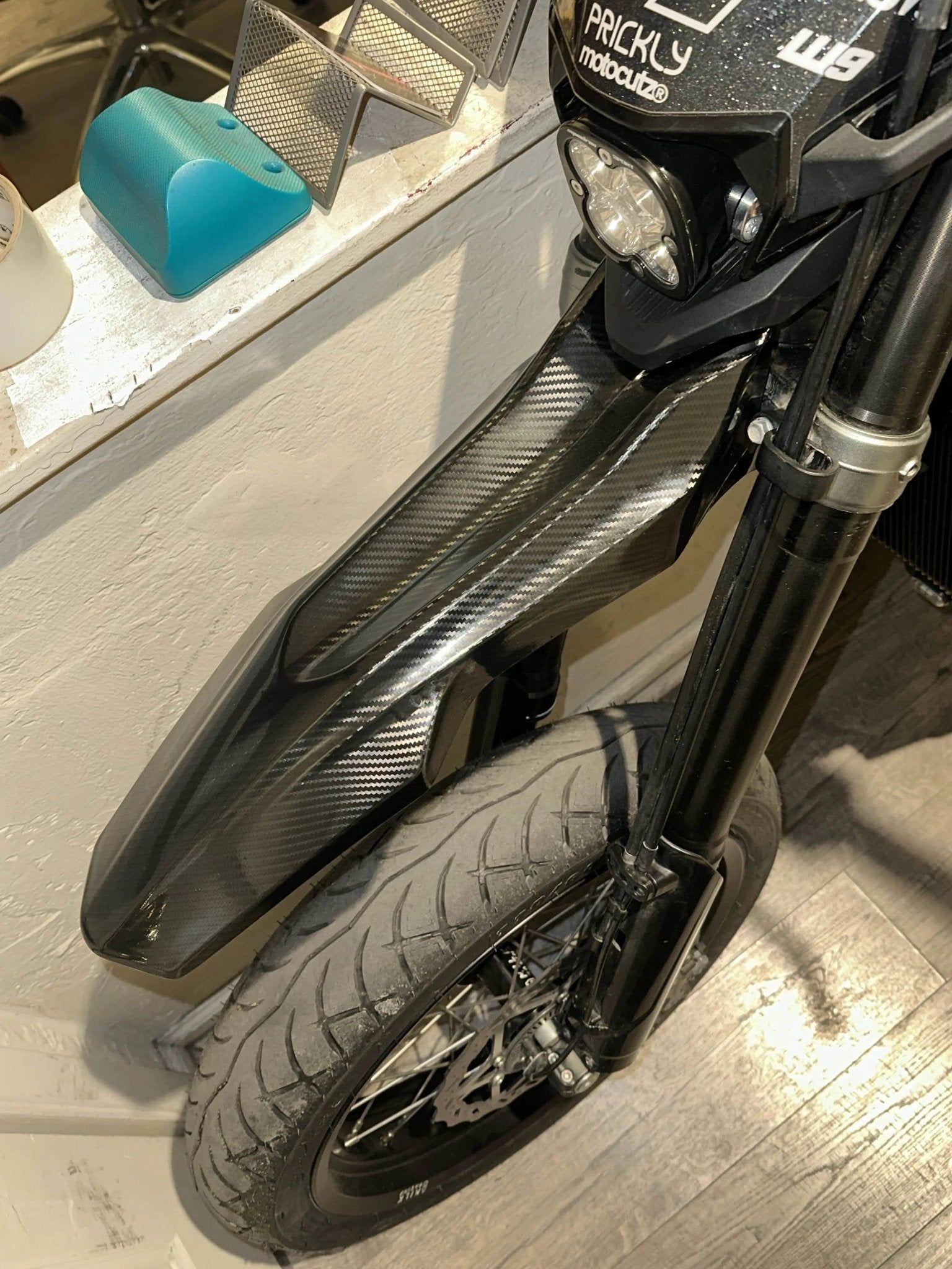 Front fender of a Surron Ultra Bee with MXwraps carbon fiber vinyl wrap kit applied for a sleek, high-performance look.