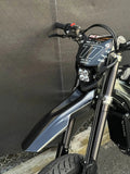 Close-up of MXwraps Surron Ultra Bee carbon fiber vinyl wrap on the front of the bike, showcasing textured black finish.