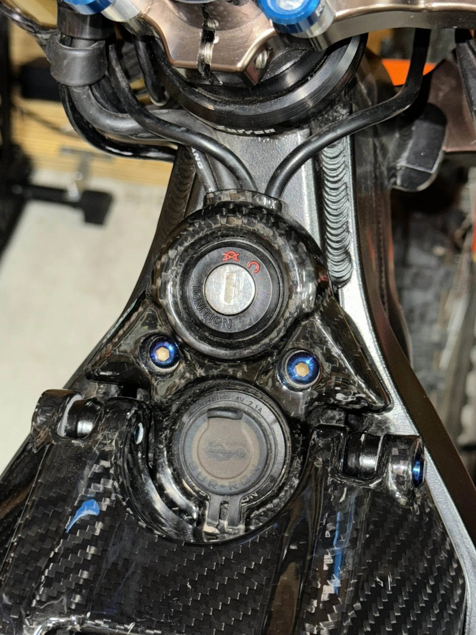 Close-up of MXwraps Surron LBX carbon fiber vinyl wrap kit on ignition panel showcasing realistic carbon fiber texture.