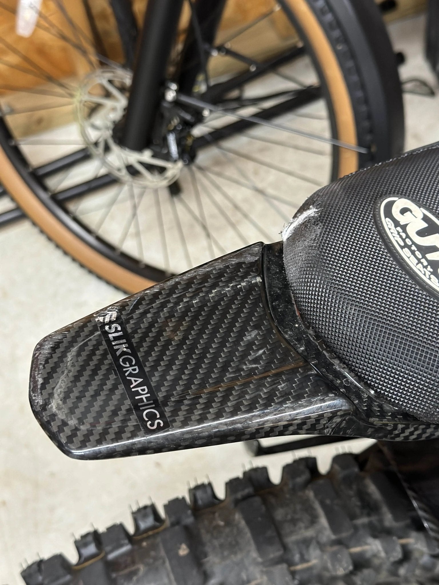 MXwraps Surron LBX carbon fiber vinyl wrap kit applied to rear seat fender, showcasing a sleek, textured carbon fiber finish.